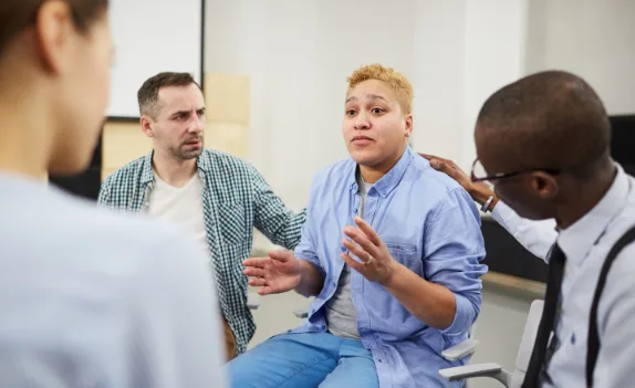 A peer support group meeting where one member shares with the group