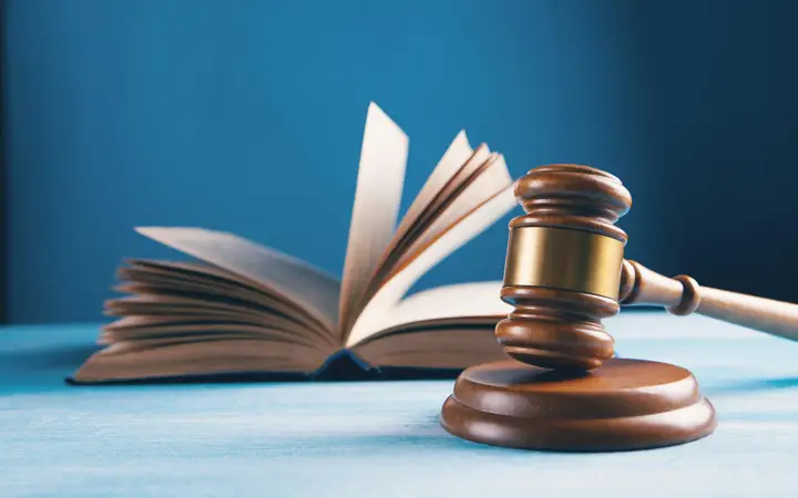 Wooden gavel beside an open book on a blue table