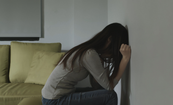 woman sitting down with head and hands against the wall in need of Outpatient Substance Abuse Counseling