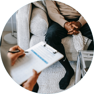 man sitting in chair in Substance Abuse Treatment session with person holding clipboard