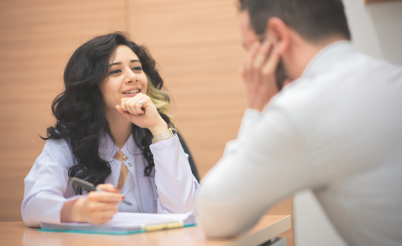 woman sitting at a table with a pen and clipboard beginning a dual diagnosis treatment session with a blurry person